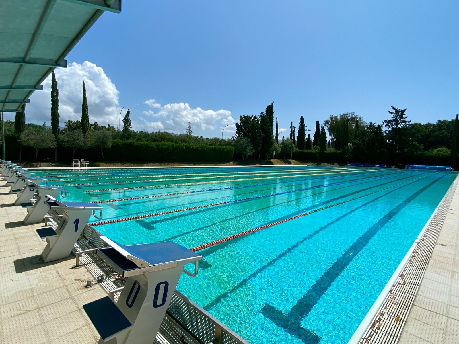  Olympisches Schwimmbecken im Coral Beach Hotel & Resort, umgeben von grüner Landschaft und strahlendem Himmel.