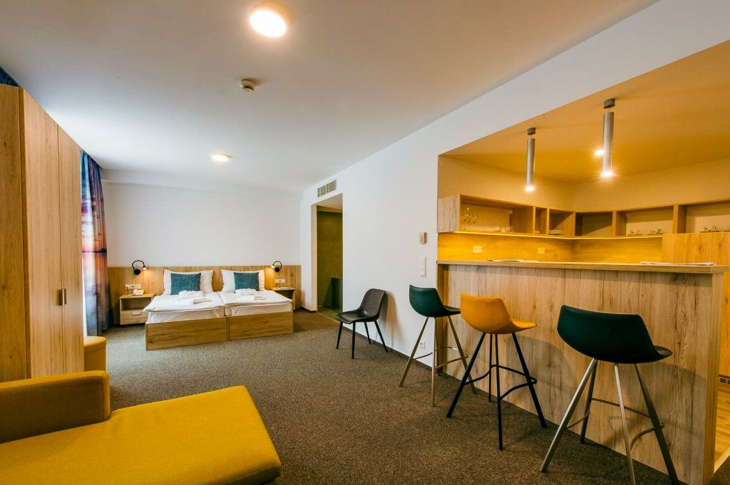 Offene Suite mit Schlafzimmer, einer modernen Bar und Sitzgelegenheiten in kräftigen Farben. Geräumig und einladend gestaltet.
