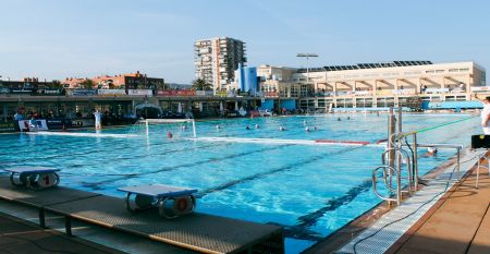 Au&szlig;enansicht des Hotels mit Balkonen und einem gro&szlig;z&uuml;gigen Poolbereich mit Liegest&uuml;hlen und Holzboden.
