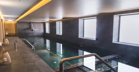 Au&szlig;enansicht eines modernen Hotelgeb&auml;udes mit Balkonen und einem begr&uuml;nten Vorgarten.