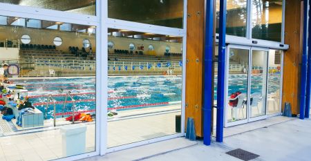 Bunte Fassade der Piscina Olimpica im Bella Italia & EFA Village, umgeben von Pinien und Grünflächen