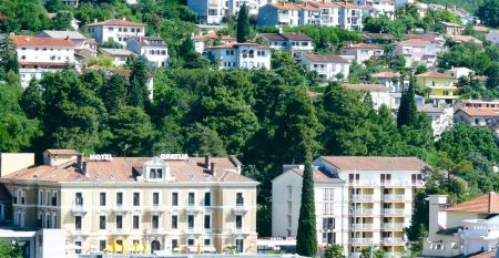 Historische Geb&auml;udeansicht des Hotels Opatija mit dekorativen Balkonen und wei&szlig;en Fenstern auf gelber Au&szlig;enfassade