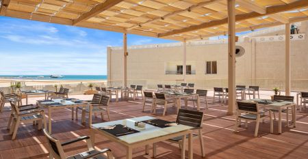 Aqua Vista Resort offers multiple outdoor pools, sun loungers, and umbrellas beneath clear blue skies&mdash;perfect for ein erfolgreiches Trainingslager in den Wintermonaten&mdash;with buildings and the sea in the background.