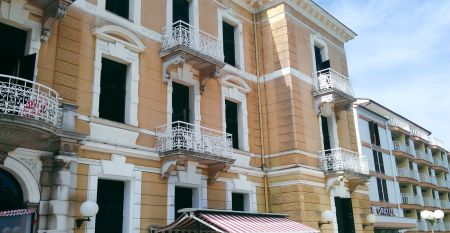 Historische Geb&auml;udeansicht des Hotels Opatija mit dekorativen Balkonen und wei&szlig;en Fenstern auf gelber Au&szlig;enfassade
