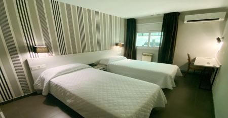 Das moderne New Hotel Colon mit mehreren Stockwerken, Balkonen und einer gepflegten Fassade, umgeben von gr&uuml;nen B&auml;umen und urbaner Architektur.