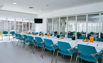 Helles Hotelzimmer mit zwei Betten mit einer roten Tagesdecke. Zudem eine Treppe, die zu einer zweiten Ebene im Zimmer führt.