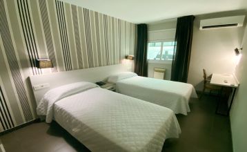 Das moderne New Hotel Colon mit mehreren Stockwerken, Balkonen und einer gepflegten Fassade, umgeben von grünen Bäumen und urbaner Architektur.