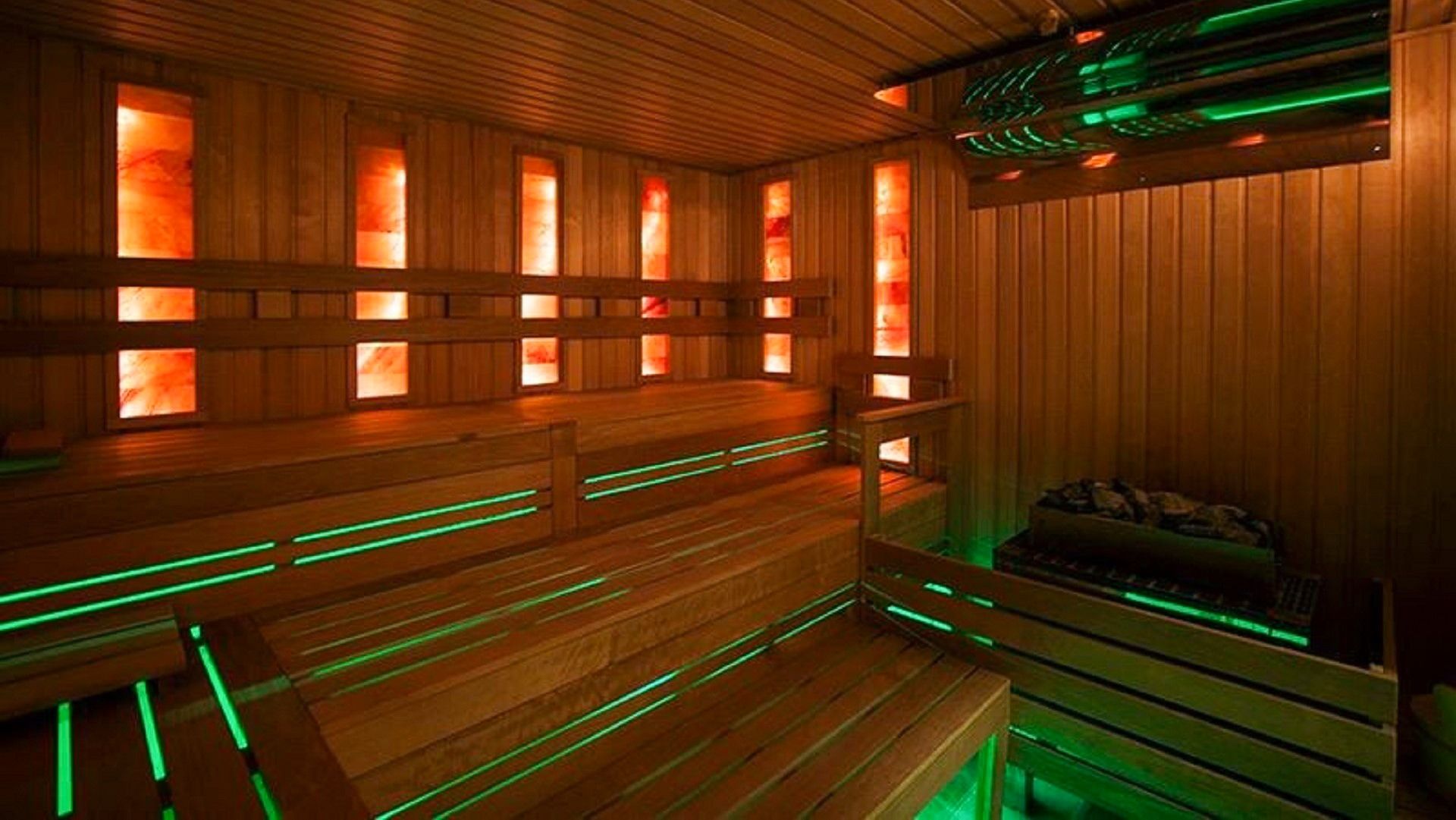 Innenansicht einer Holzsauna mit beleuchteten Salzwänden und grüner LED-Beleuchtung unter den Holzbänken.