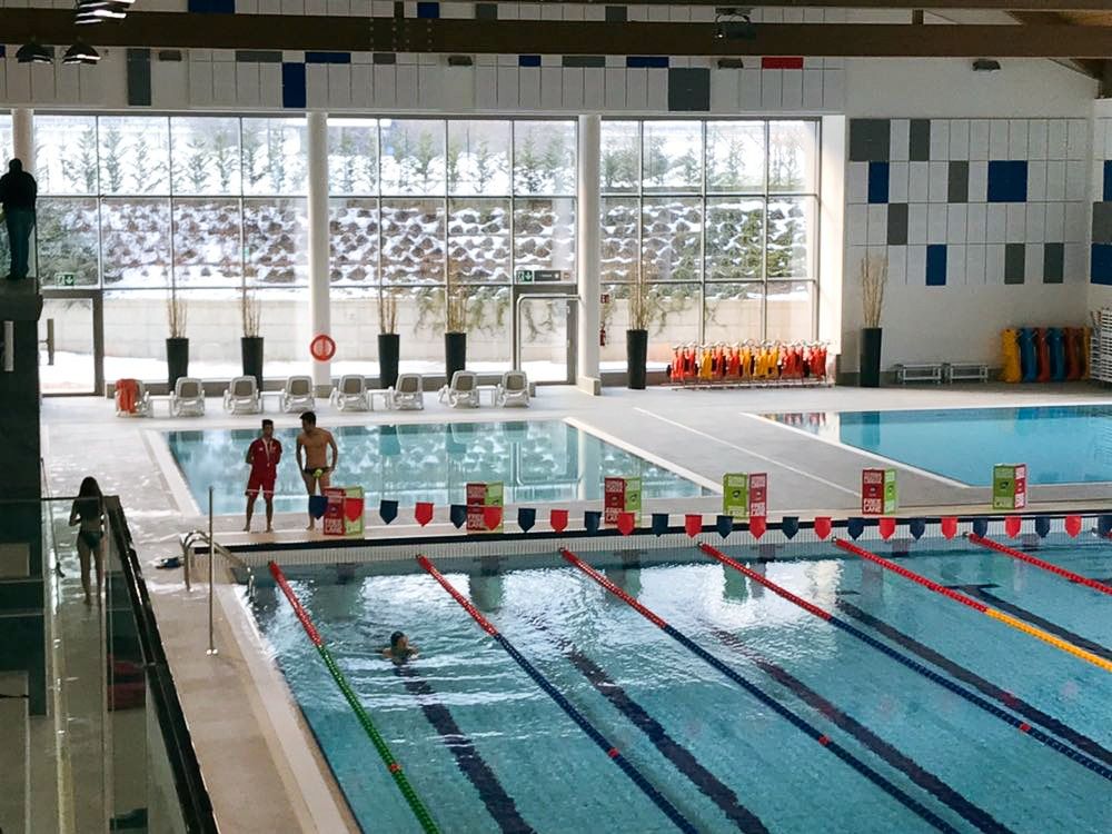Blick auf mehrere Pools in einer großen Schwimmhalle beim Ostello Sportivo