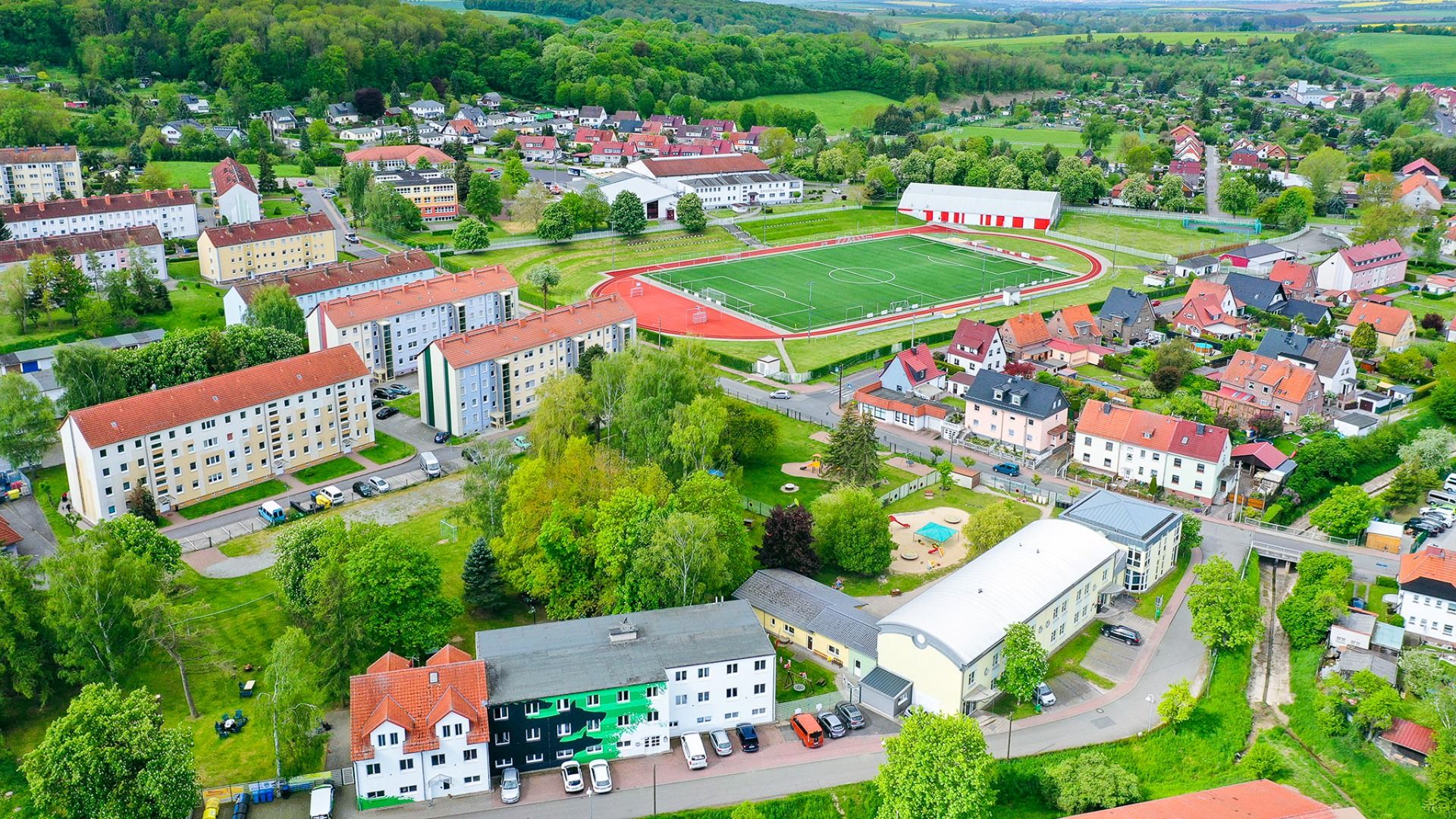 Luftaufnahme des Sportcampus Schlotheim mit umliegenden Wohnhäusern, Sportanlagen und einer modernen Fußball- und Leichtathletikanlage