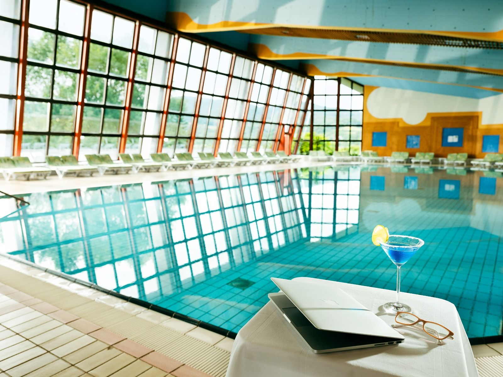 Ein einladender Indoor-Pool mit großen Fensterfronten, die viel natürliches Licht hereinlassen, und einer entspannenden Atmosphäre.