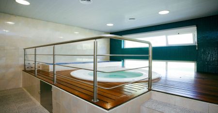 Helles Hotelzimmer mit zwei Betten mit einer roten Tagesdecke. Zudem eine Treppe, die zu einer zweiten Ebene im Zimmer f&uuml;hrt.