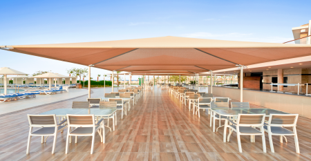 Aqua Vista Resort offers multiple outdoor pools, sun loungers, and umbrellas beneath clear blue skies&mdash;perfect for ein erfolgreiches Trainingslager in den Wintermonaten&mdash;with buildings and the sea in the background.