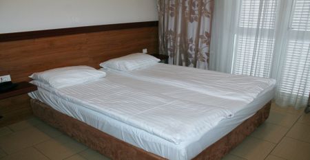 Au&szlig;enansicht des Hotels Aquapark Zusterna mit rosa Fassade, Balkonen und der slowenischen Flagge.