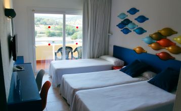 Hotelanlage mit Poollandschaft, Palmen, kleinen Brücken und Blick auf die umliegenden Berge.