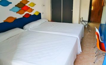 Weitläufiger Hotelgarten mit geschwungenem Pool, Palmen und einer Brücke, umgeben von Hotelgebäuden.