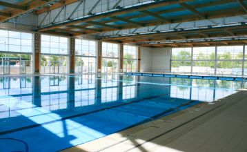 Weitläufiger Hotelgarten mit geschwungenem Pool, Palmen und einer Brücke, umgeben von Hotelgebäuden.